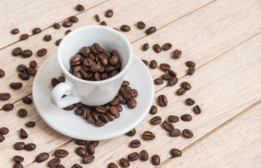Cup of coffee beans with a spoon and saucer on a white background with the outline of more coffee beans