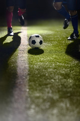 Two soccer players running towards a soccer ball