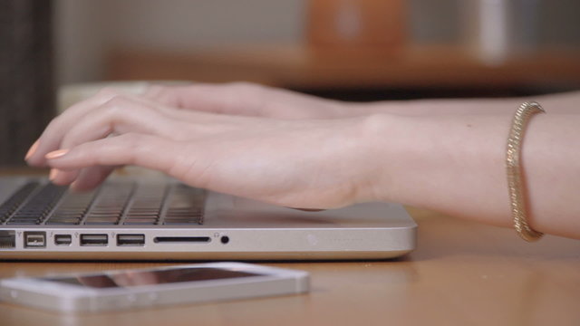 Closeup of a female hands busy typing on a laptop.