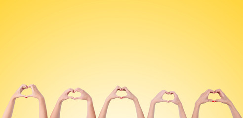 Young people makes hearts using fingers on yellow background