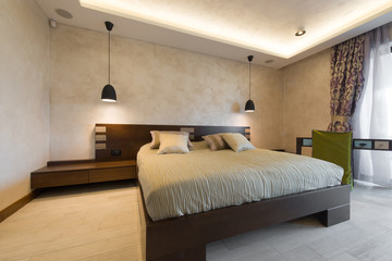 Double bed in brown colored modern bedroom interior