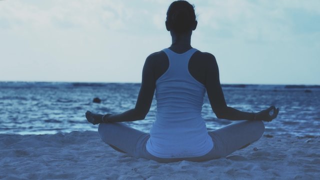 Woman sitting in yoga lotus pose on the caribbean beach at dawn, Mahahual, Mexico. 4k