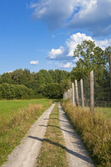 Fototapeta na wymiar View of a path with a fence in the green countryside in Sweden