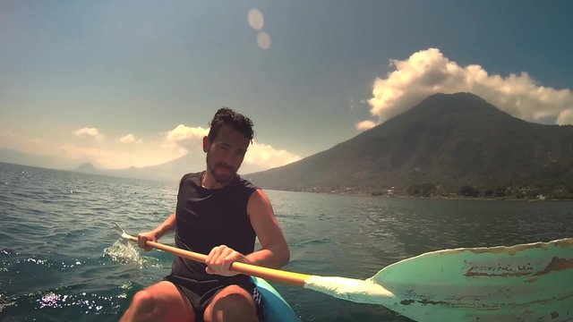 Caucasian man kayaking on the Lake Atitlan towards the San Pedro volcano