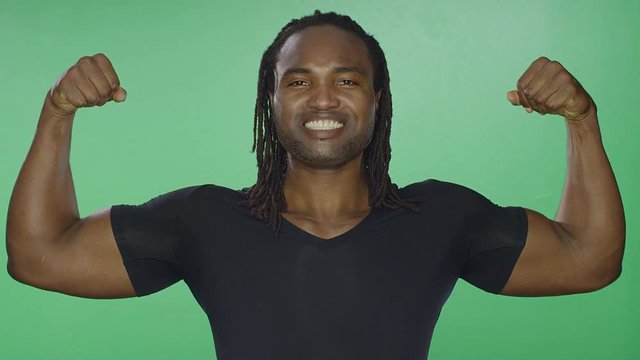 Athletic black man flexing his arms, on a green screen studio background