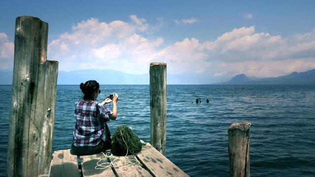 Woman taking photos to the beautiful panorama of Lake Atitlan, Guatemala. 4k