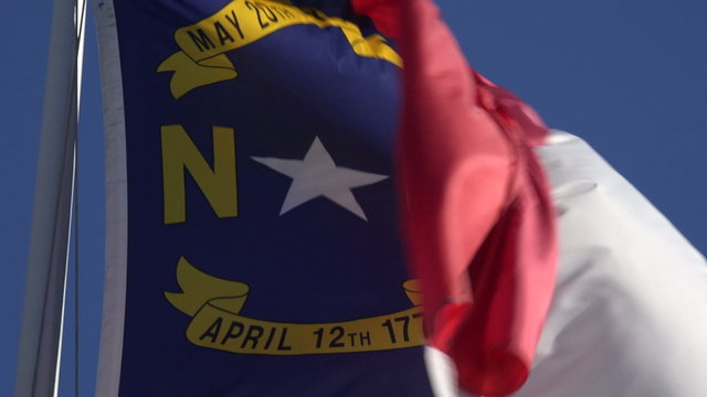 North Carolina flag in wind with blue sky background, NC, USA