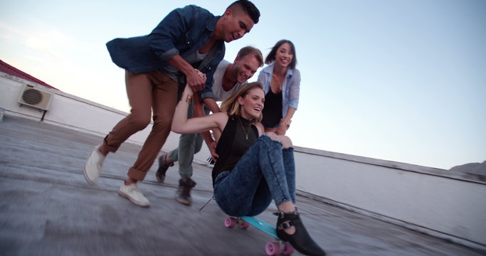Group of friends having fun a the rooftop with a skateboard