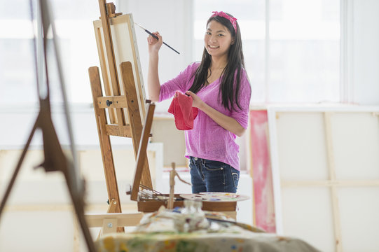 Mixed race teenage girl painting in studio