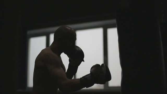 Sports: Silhouette of man is practicing kick in a boxing gym