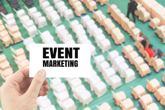 word event marketing on white card in hand on blurred rows of chair background