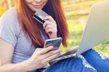 Mobile payments. Female (Focused) hands using smartphone and (Blurred) credit card with laptop for...