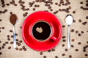 Coffee cup with coffee and sugar spoons on gunny textile