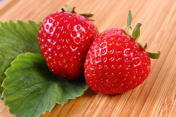 Strawberry with leaves on wooden surface