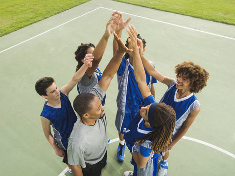 Basketball team high fiving on court - Powered by Adobe