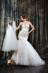 Fototapeta na wymiar pretty bride near hanger with dress