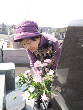 お彼岸にお墓に花を添える80歳の母
