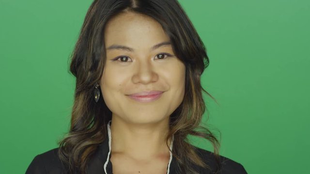 Young Asian woman smiling and laughing, on a green screen studio background