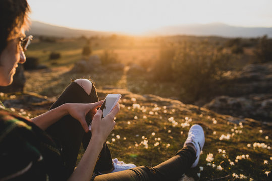 Woman sitting on a rock looking at the mobile