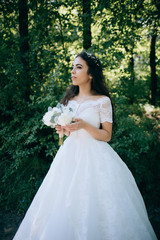 Fototapeta premium Beautiful sensual bride with rustic wedding hairstyle in the forest. Outdoor portrait of young gorgeous bride. Wedding. Shadow on the back
