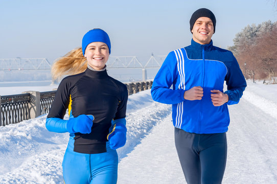 Runners. Young Running Couples. Sport Man & Woman Jogging On Winter Embankment