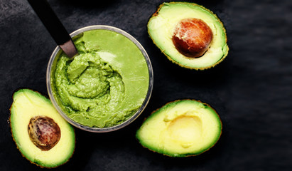 Guacamole with ripe avocados over black background. Top view.