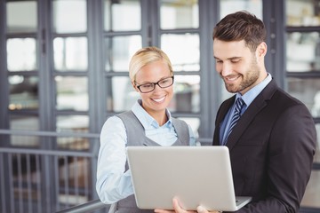 Business people smiling while looking at laptop