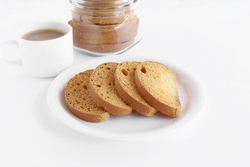 Healthy snack rusk, made from whole-wheat flour, in a plate and a cup of coffee and a bottle containing rusks.