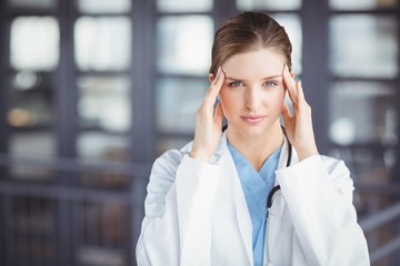 Portrait of tensed female doctor with head in hands 