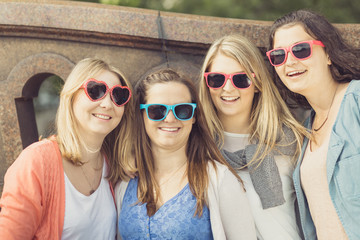 Vier junge Frauen mit Sonnenbrille posieren