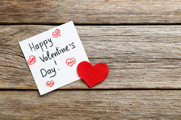 Red heart and sheet of paper on a grey wooden table