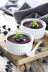 Delicious blueberry mousse in bowls on grey wooden table, on cut