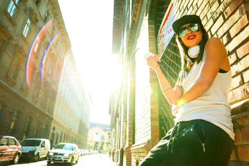 Hip hop girl with headphones in a urban environment - obrazy, fototapety, plakaty
