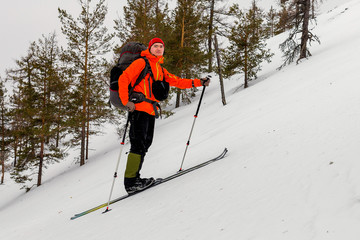Fototapeta na wymiar Skier Mountain hiker climbs at a very steep hill, with a heavy b