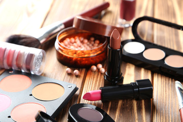 Makeup brush and cosmetics on brown wooden table