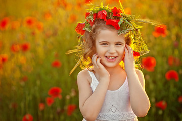 Little girl in poppy field on sunset. Soft focus. Smiling girl.