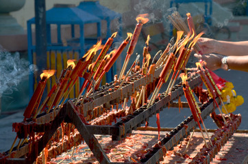 People burning incense and red candle for pray god at Suphanburi city pillar shrine in Suphanburi, Thailand.