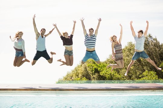 Group of friends jumping at poolside
