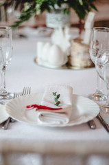 Wedding ceremony decoration in the restoraunt. The composition of green sprig eucalyptus flowers on festive table with white tablecloth, decorated rustic style.