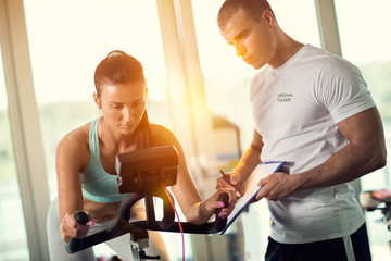 Personal trainers in the gym giving instruction and help to attr