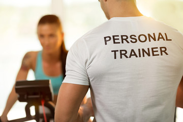 Personal trainer with woman on cycling machine at the gym