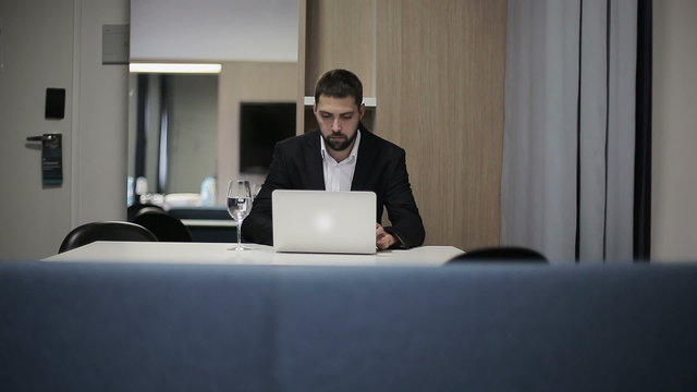 Businessman works at laptop in a hotel room