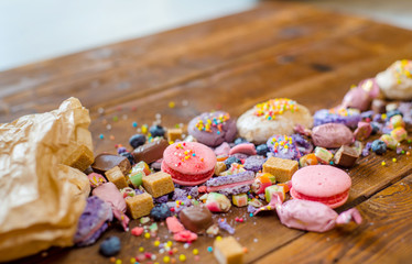 bright candy spilled out of the bag on a wooden table with a teapot and cups