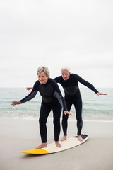 Senior couple surfing on beach