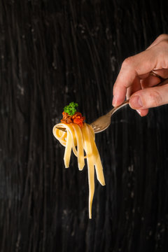 Mans Hand Holding A Fork With Pasta