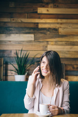Young beautiful woman sitting at cafe and talking on the mobile phone