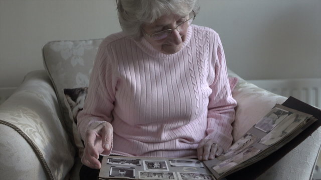 Senior woman looks at old photographs in album