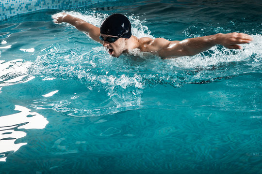 Muscular young man swims the butterfly