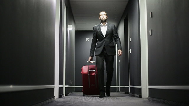 Businessman with a suitcase in a corridor of hotel