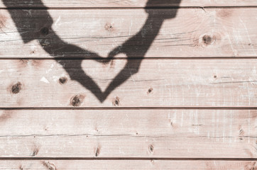 Shadow in shape of heart on an old wooden background